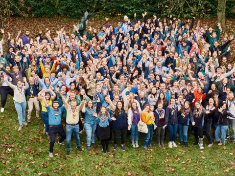 A group of people smile at the camera and raise their hands.