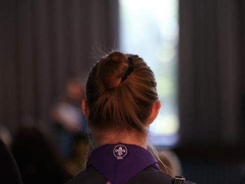 A woman with her hair up wears a purple Scout scarf.