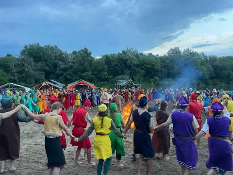 Young people dressed in colourful clothes dance holding hands.