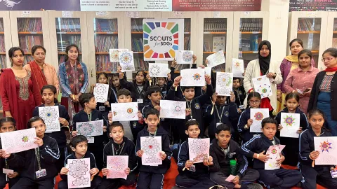 Un groupe de jeunes élèves de l'école internationale Vrinda, à New Delhi, montrant leurs mandalas colorés. Ils sont rassemblés dans la bibliothèque avec « Scouts pour les ODD » bien en évidence, montrant leur participation au défi de la santé mentale du Scoutisme mondial.