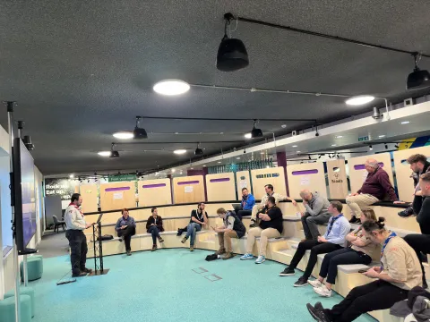 A group of adults listen to the presentation of a man.