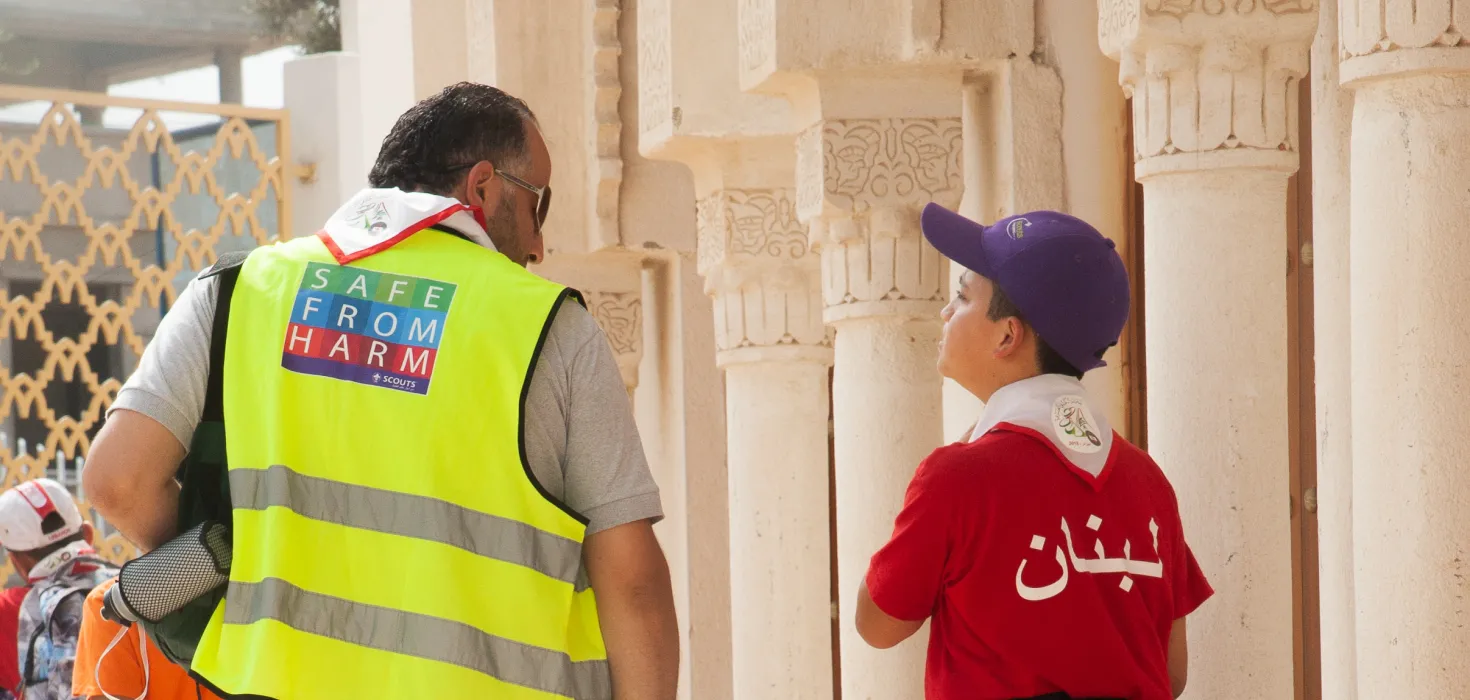 a scout walking with a leader that is wearing a safe from harm vest
