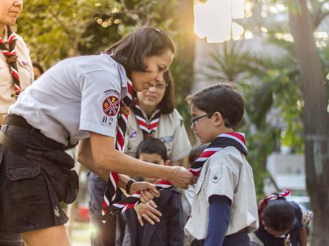 A leader giving a scout a scarf