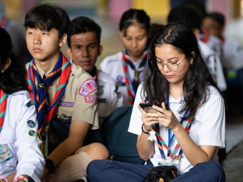 A Scout sits with a group looking at her phone