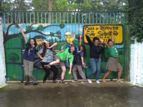 Scouts in Sao Paolo of União dos Escoteiros do Brasil pose in front of a colourful gate while working on a project to help the environment and easing poverty
