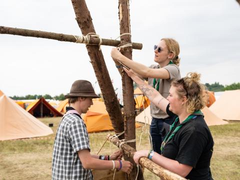 3 Scouts at the Denmark National Jamboree work together to assemble a pioneering project