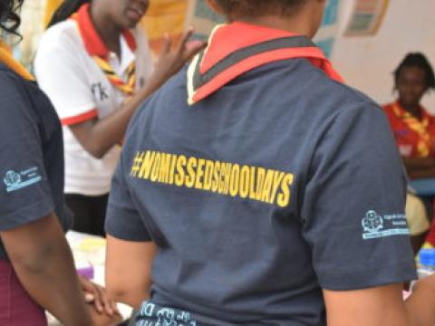 Scout ougandais portant un t-shirt sur lequel on peut lire en jaune : Pas de jours d'école manqués.