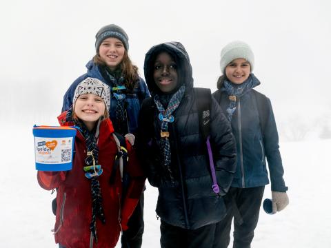 Four young Scouts and Guides stand showing a box used for raising funds.