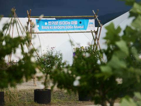The Ban Ki-moon SDG Maeul entrance is seen behind green foliage of a garden at the World Scout Jamboree in West Virginia, USA