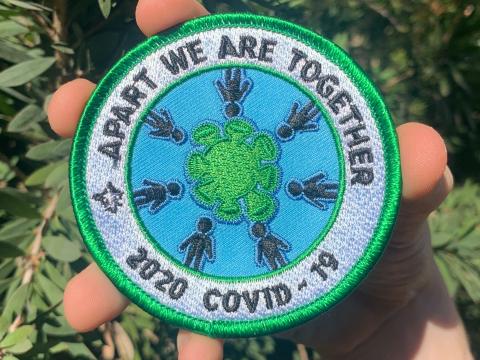 Determined to find a way to support in the chaos, Katelyn steps up. She designs badges and sells nearly 1,000 of them to raise funds for frontline workers. The badge is pictured here - it says "Apart we are together 2020 COVID-19"
