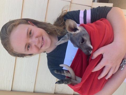 Seeing the impact on local wildlife firsthand, Molly takes the initiative to band her whole community together and lead the charge in sewing and cutting countless pouches for orphaned wildlife. Molly pictured holding a baby kangaroo in a homemade pouch.