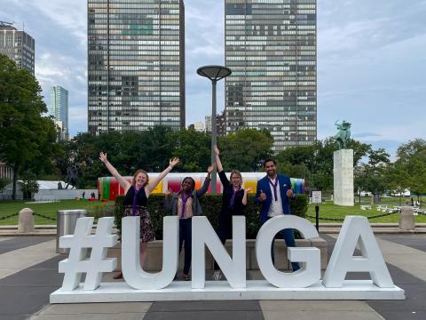 Three World Scouting Youth Representatives, from Kenya, Lithuania and Australia, post in front of a #UNGA sign at the United Nations with Ahmad Alhendawi, Secretary General of WOSM