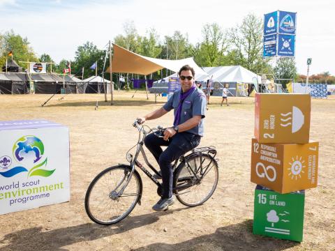 WOSM Secretary General Ahmad Alhendawi rides a bike at the SDG tents at the World Scout Jamboree