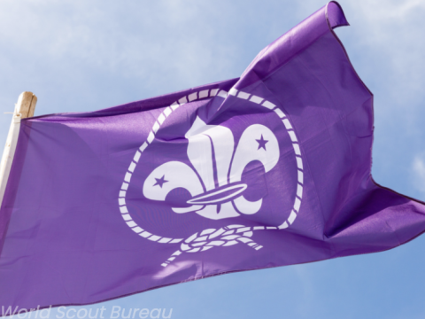 La bandera morada de la OMMS ondea con un cielo azul de fondo