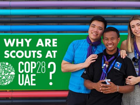 Kek, Lucas and Laura pose in front of a rainbow coloured wall with text saying "Why are Scouts at COP28?"