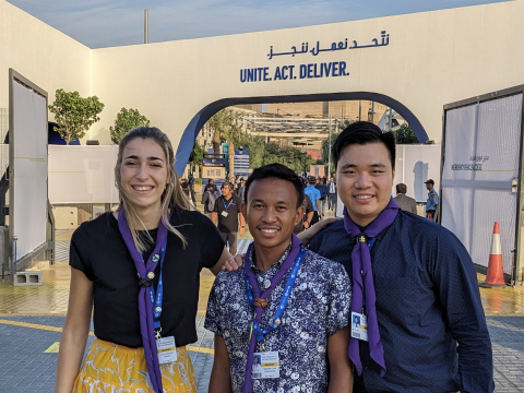 Scouts Lucas, Kek and Laura stand in front of a COP28 sign reading Unite, Act, Deliver
