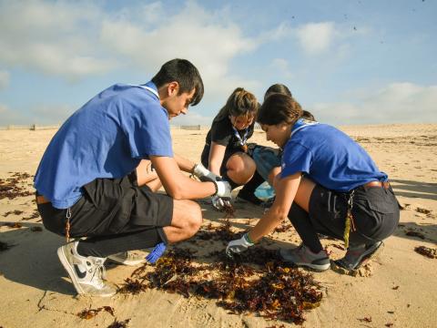 3 young people picking up litter from a beach.