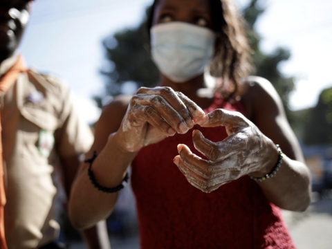Woman wears mask as she washes hands with soap