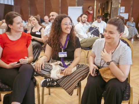 Inês sitting between two women, smiles.