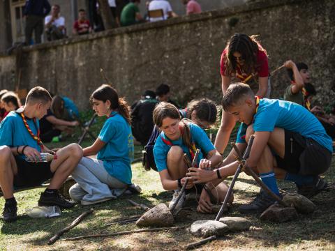 four young people create small constructions with sticks and ropes.
