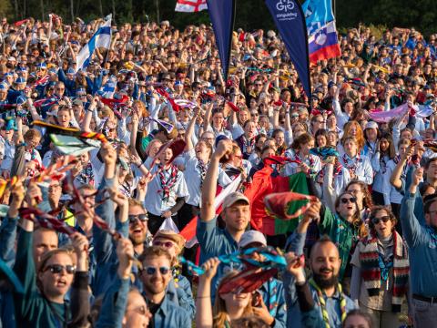 Participants at Roverway 2024 chear and hold their scarves in the air.