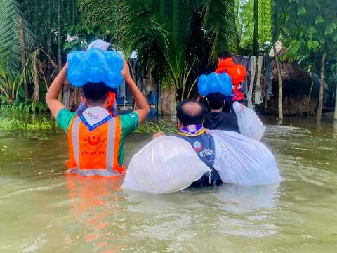 Scouts carrying belonging through flood waters
