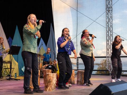 Laura signs on the stage of Roverway 2024 together with three other Scouts.