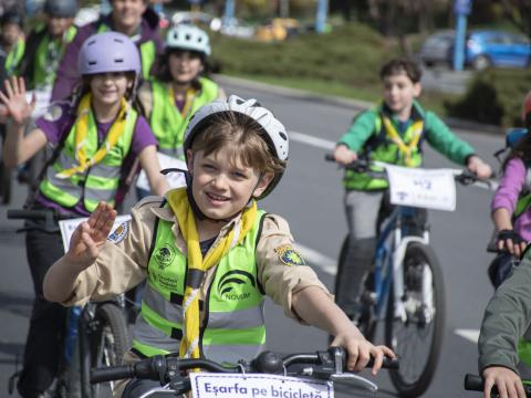 A young Scout makes the Scout salute while riding a bike.