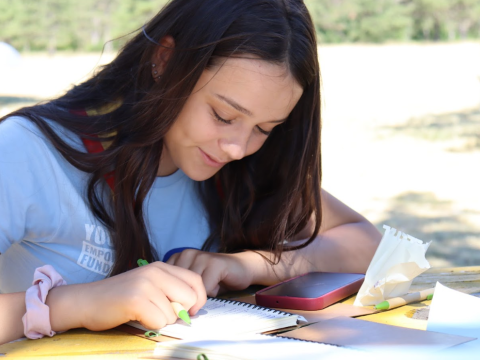 Ana is writing on a notebook.