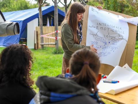 A facilitator points at a flipchart while participants look at it.