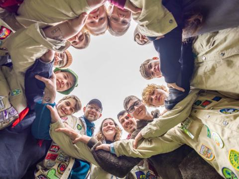 Scouts of different ages intertwin arms in a circle.