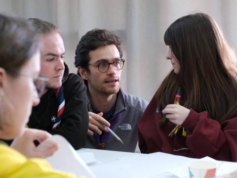 Scouts having a conversation around a table.