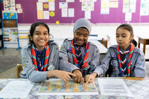 Three girl scouts look at a world map together during JOTA-JOTI