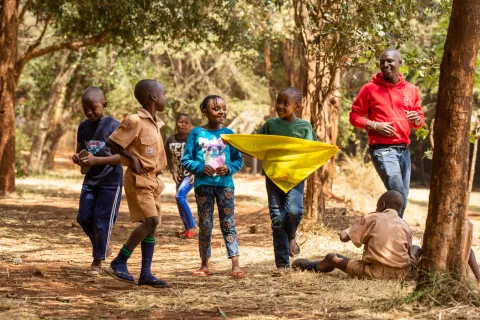 An adult volunteer walks outside with young Scouts in Kenya