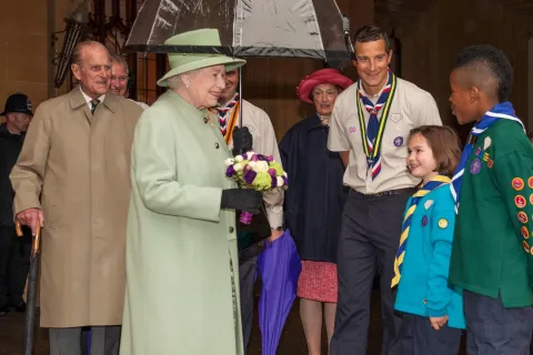 La reine Elizabeth se tient à côté de Bear Grylls et de jeunes scouts