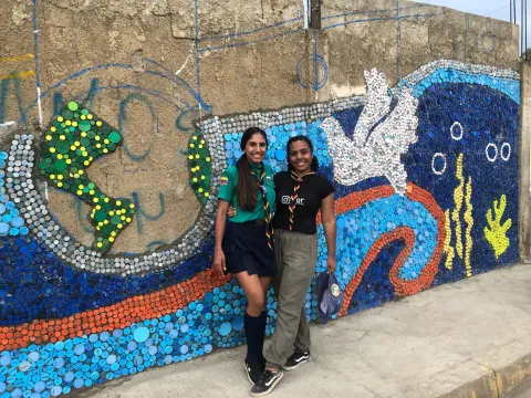 Daniela and a fellow Scout pose in front of the partially-completed mural during two days of work with 50 volunteers.