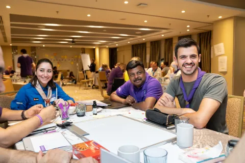 Trois bénévoles scouts adultes assis à une table rient pendant un atelier.