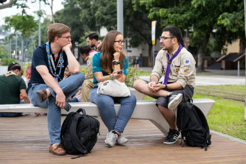 Trois Scouts discutent sur un banc à l'extérieur pendant le forum sur l'éducation non formelle au Brésil.