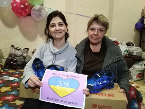 Two Ukrainian Scout volunteers receive donations of new shoes from Scouts in Spain, along with drawings representing Scouting, peace and solidarity