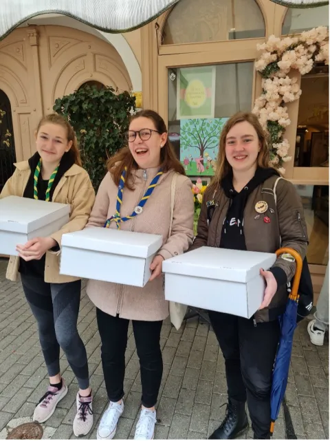 Lana et deux Scouts tiennent une boîte blanche.