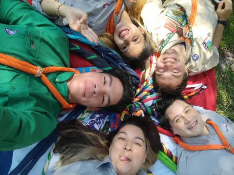 Scouts from the Migrant Scout programme in Chile lay together in the grass