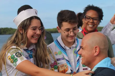 A Scout puts a scarf on another Scout on their sailboat in Brazil