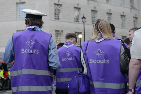 Three Scouts wearing purple high visibility jackets with the scouts fleur de lis.