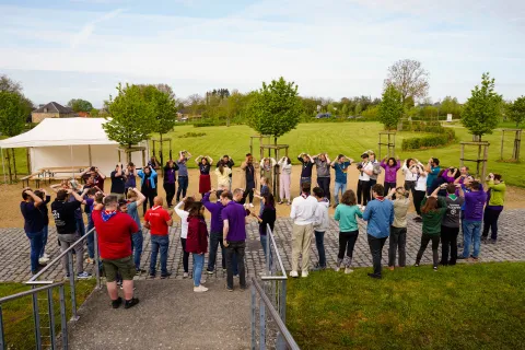 People wearing Scout scarves stand in a circle.