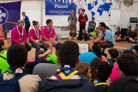 A group of young people wearing scarves talk in front of others.