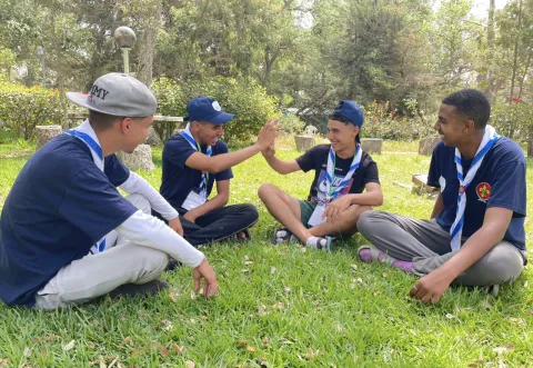 Scouts sit in the grass together during the Arab Parajamboree
