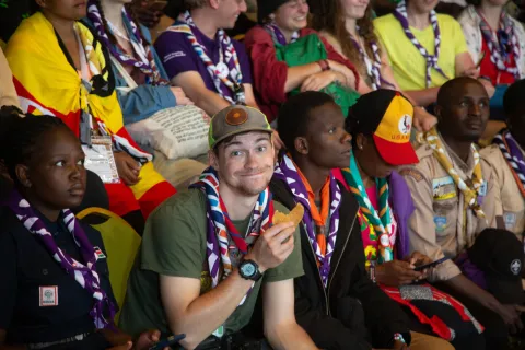 Scouts from around the world don their uniforms at the Africa Rover Moot, while one Scout looks at the camera enjoying a snack