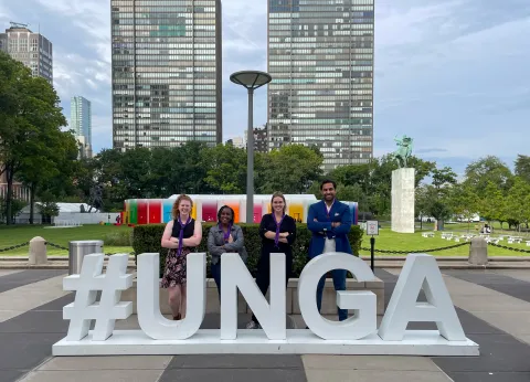 Three World Scouting Youth Representatives, from Kenya, Lithuania and Australia, pose in front of a #UNGA sign at the United Nations with Ahmad Alhendawi, Secretary General of WOSM