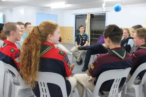Meg Cummins, WOSM Youth Representative, sits in a circle with other Scouts
