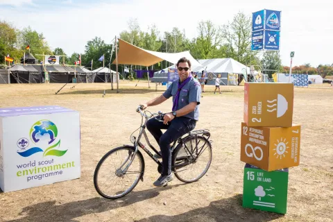 WOSM Secretary General Ahmad Alhendawi rides a bike at the SDG tents at the World Scout Jamboree in South Korea